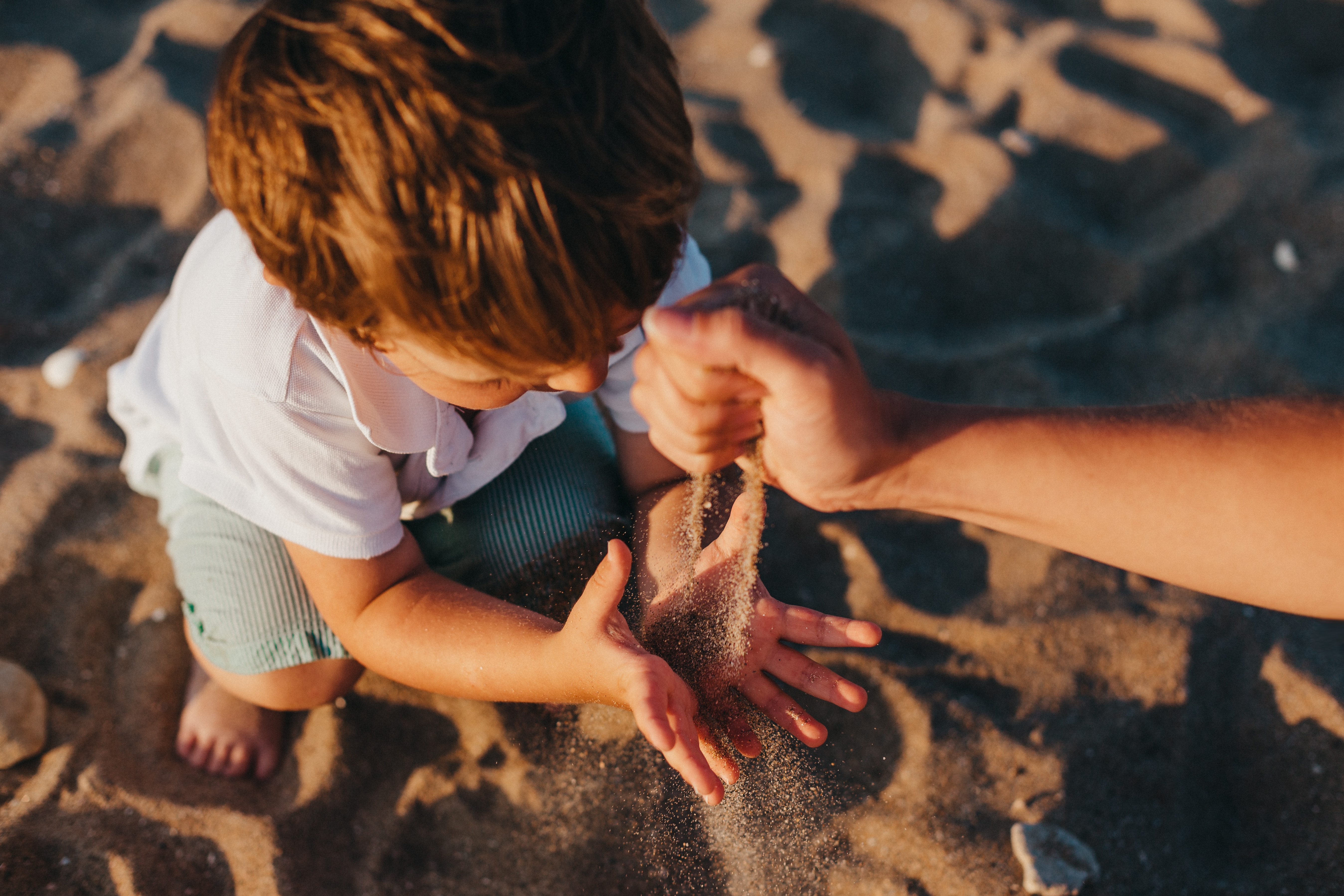 En liten gutt som leker i sanden sammen med faren sin