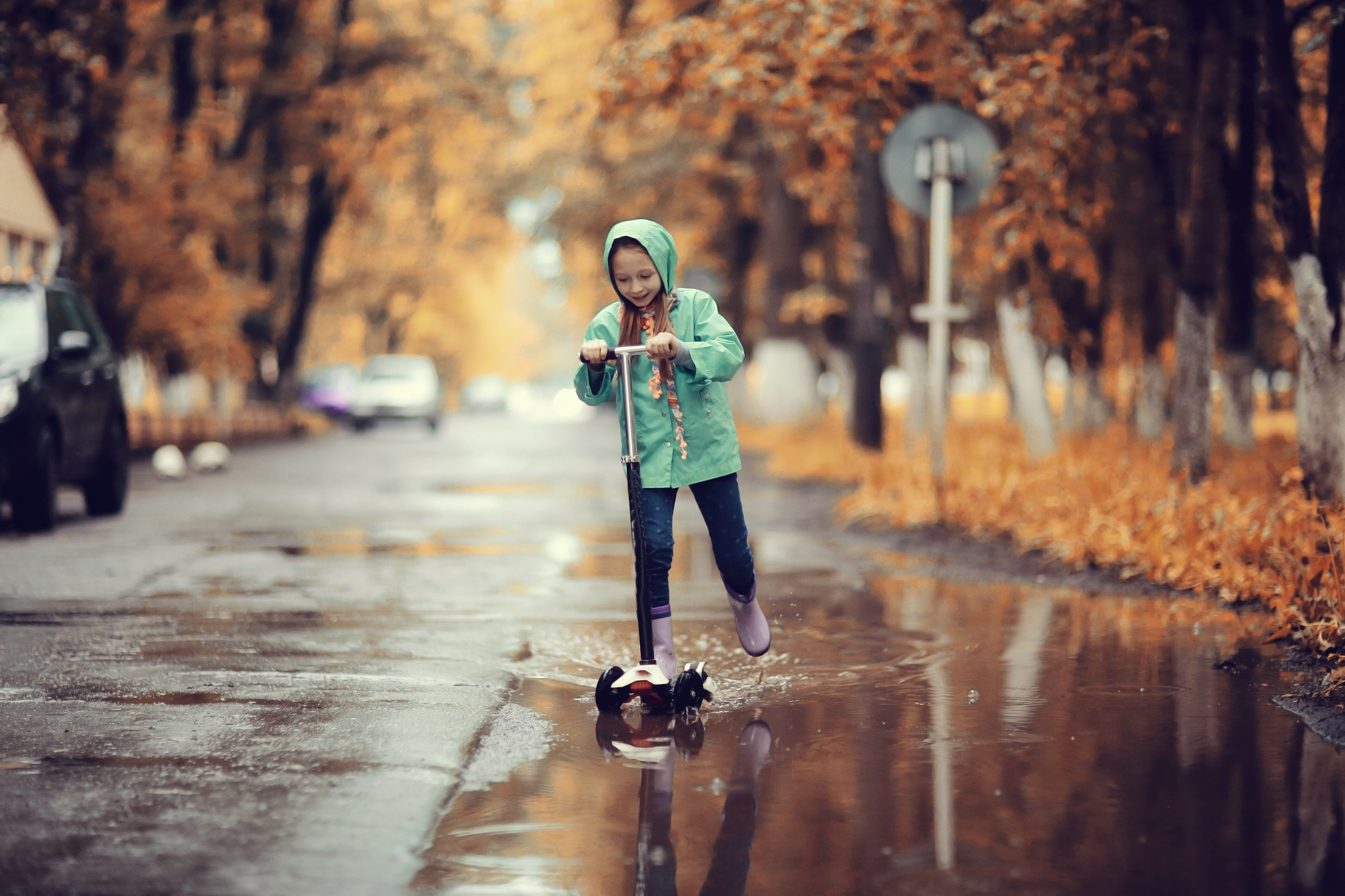 Jente på sparkesykkel i regnet